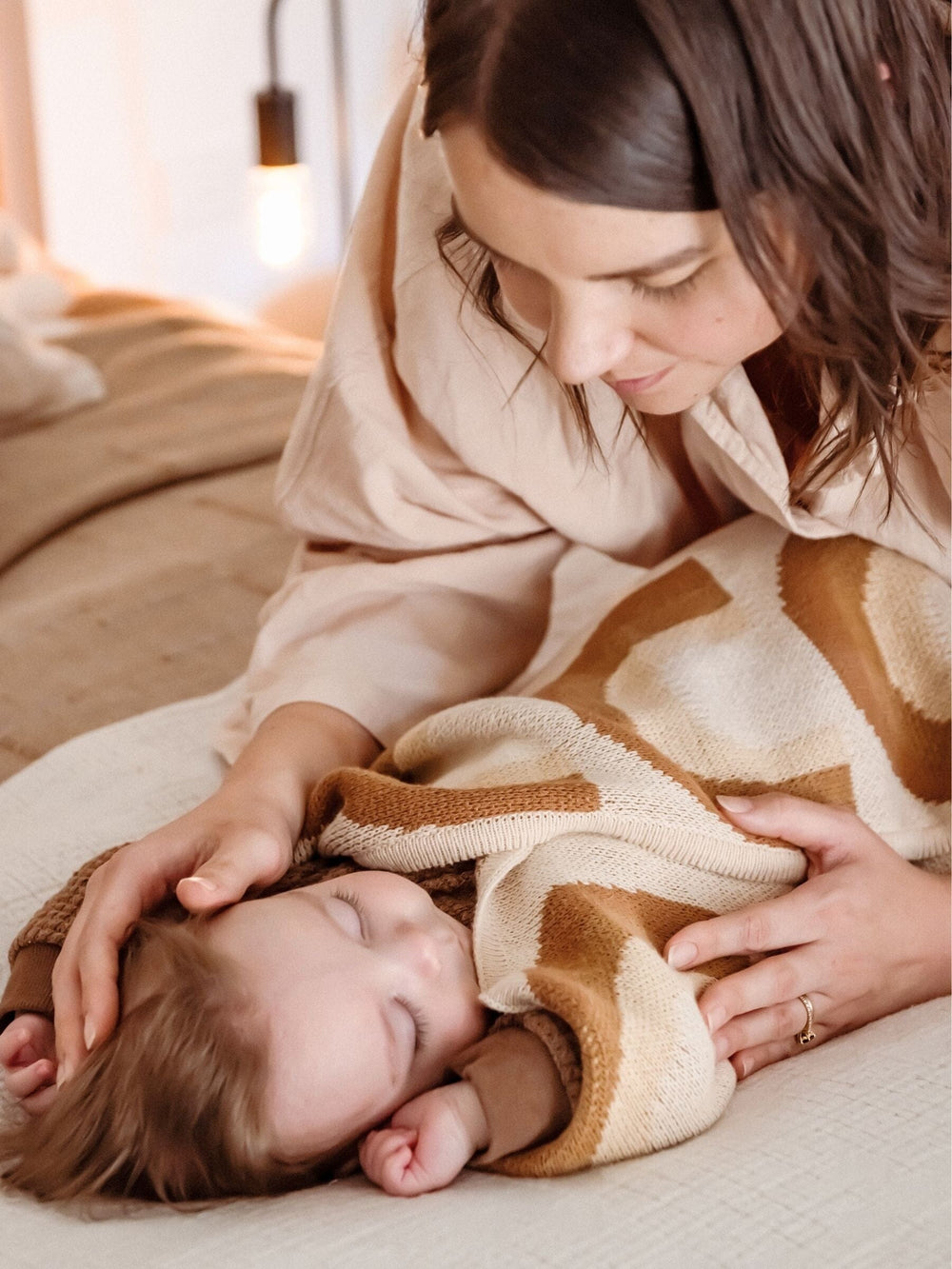A parent cuddling a baby with the Rainbow organic cotton blanket