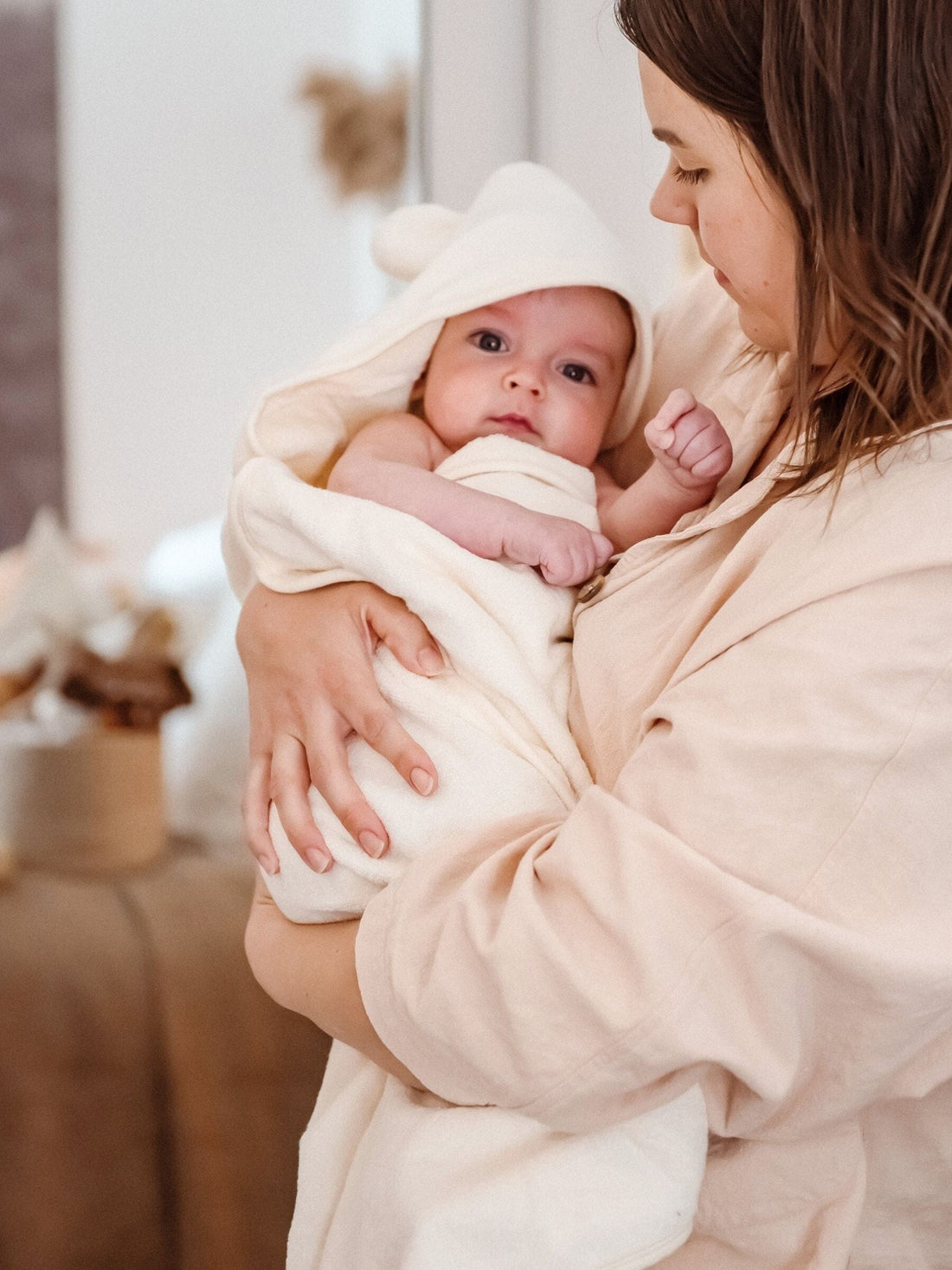Mother holding her baby wrapped in the Ivory Kiin hooded towel
