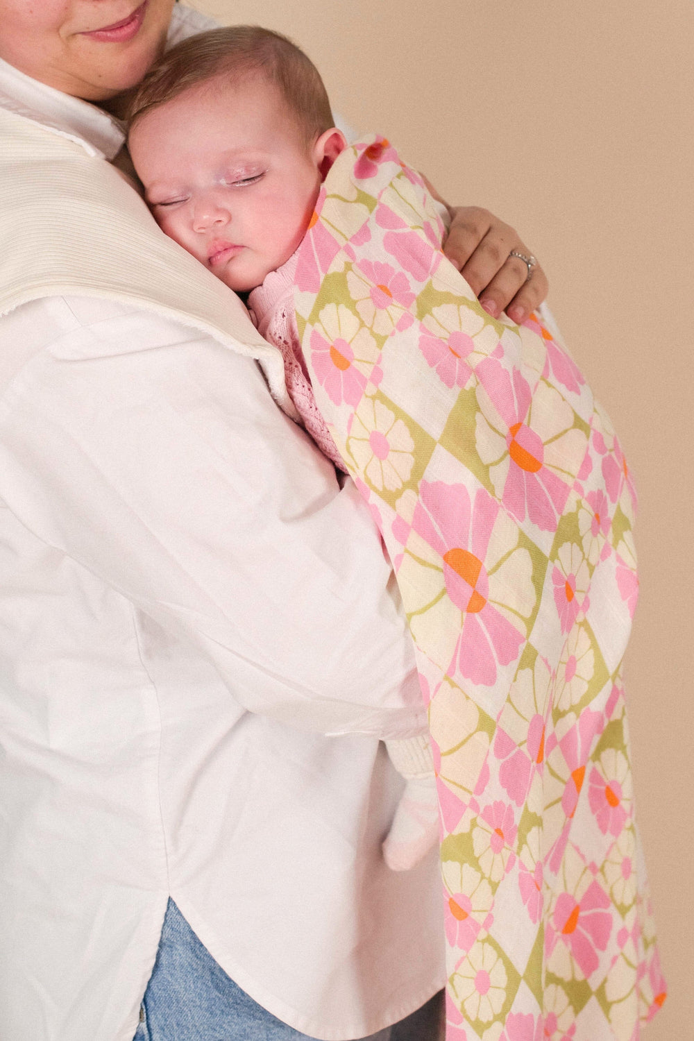 A newborn cuddled in the Whimsy organic muslin swaddle